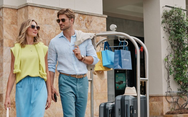 Man and women standing in front of hotel with luggage cart